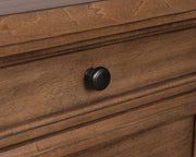 Close-up of Ashley Furniture Chadworth nightstand with detailed wood knob and dark wood finish.
