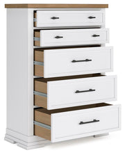 Ashbryn Chest of Drawers by Ashley Furniture, angled open view showing multiple drawers and wood finish in a modern bedroom setting.