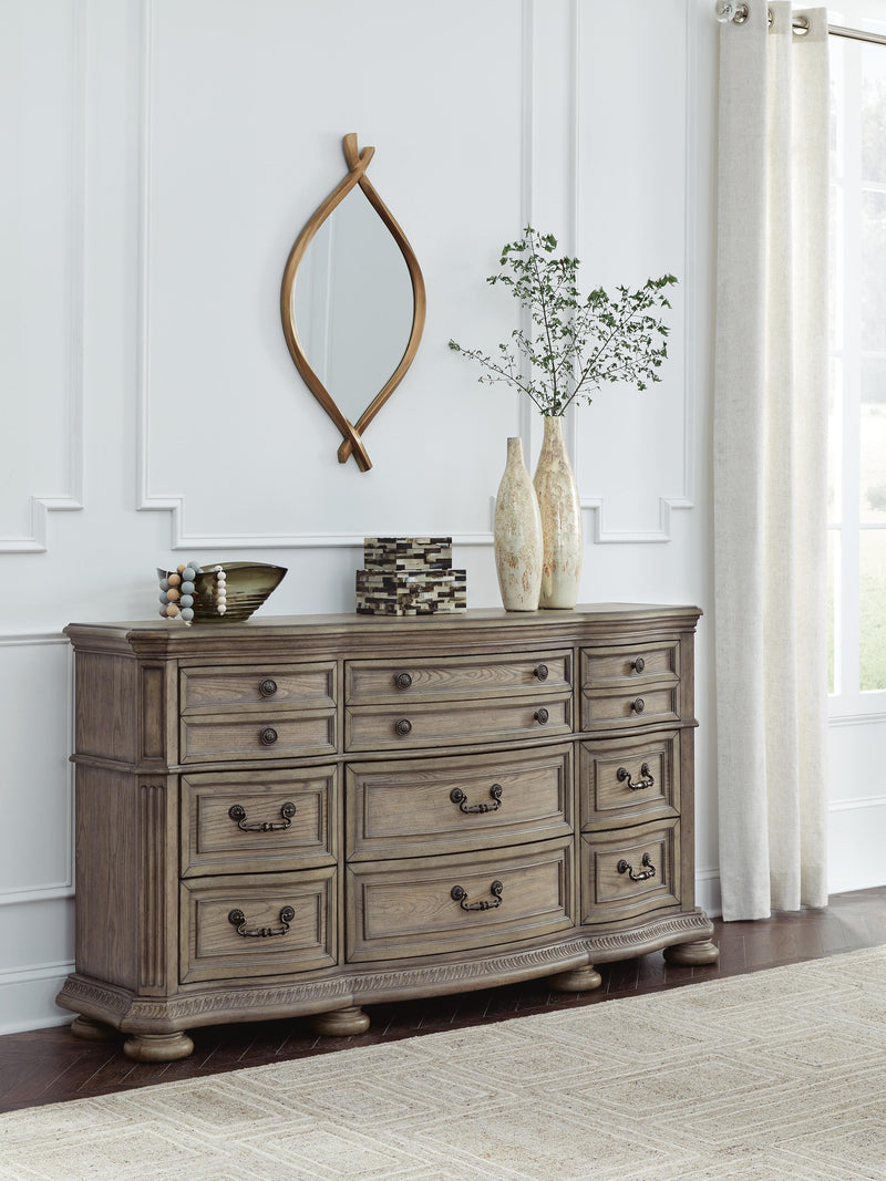 Ashley Furniture Ardenfield dresser with multiple drawers and a warm wood finish, shown in a spacious bedroom setting.