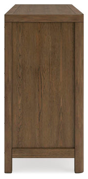 Ashley Furniture Cabalynn Dresser with sleek wood finish and multiple drawers, shown from a side angle in a modern bedroom setting.