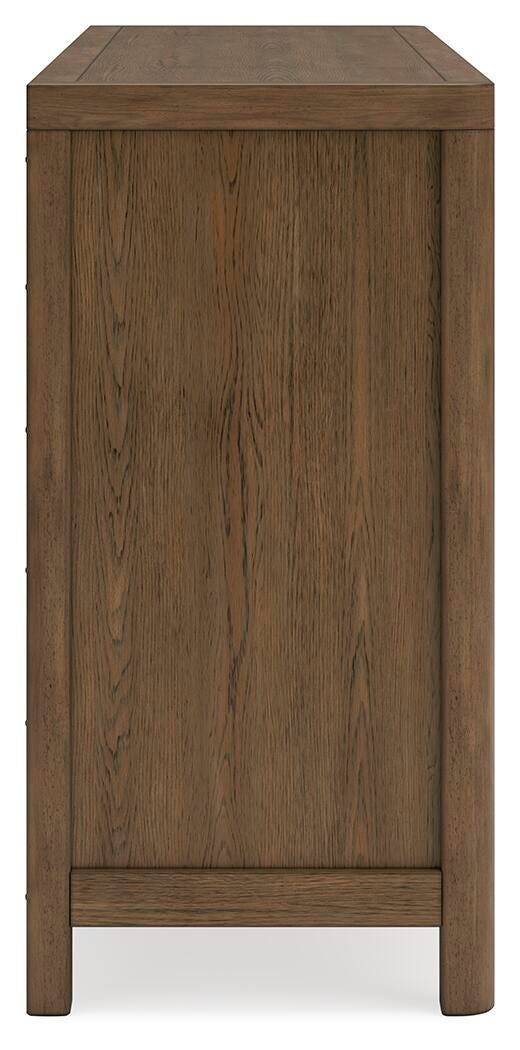 Ashley Furniture Cabalynn Dresser with sleek wood finish and multiple drawers, shown from a side angle in a modern bedroom setting.
