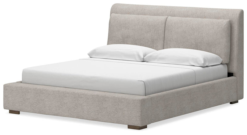 Ashley Furniture Cabalynn upholstered bed with tufted headboard and neutral fabric, shown from a side angle.