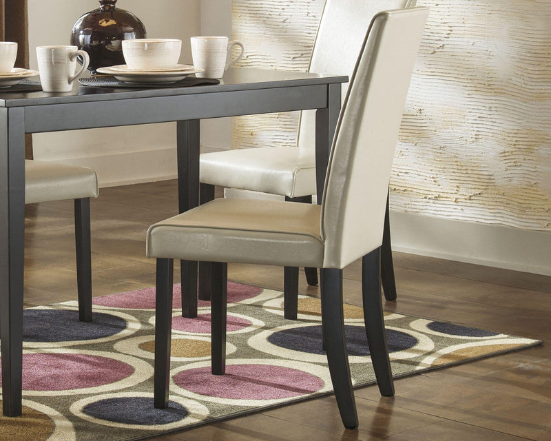 Ashley Furniture Kimonte dining chair with dark wood finish and upholstered seat, shown from a side angle.