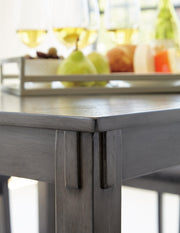 Ashley Furniture Bridson counter height dining table with four matching bar stools, showcasing a modern wood finish and sturdy design.