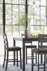 Ashley Furniture Bridson counter height dining table with four matching bar stools, showcasing a modern wood finish and clean design.