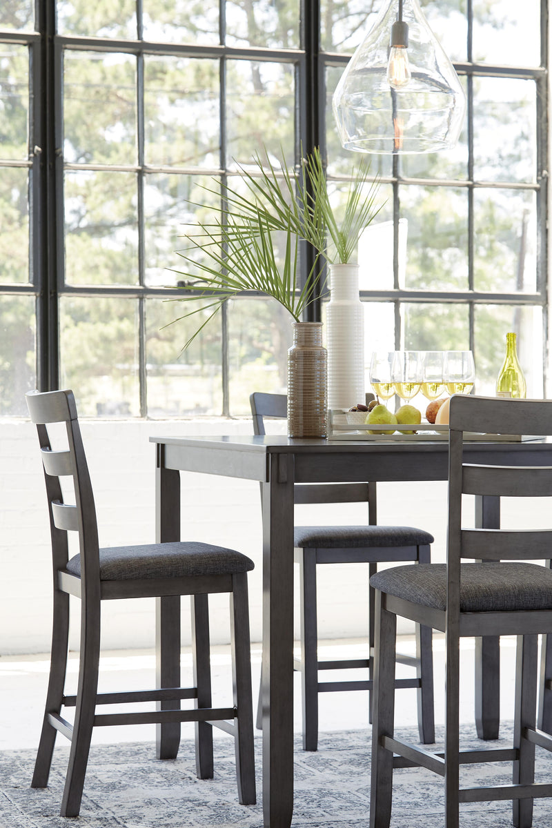 Ashley Furniture Bridson counter height dining table with four matching bar stools, showcasing a modern wood finish and clean design.