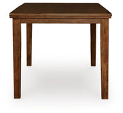 Ashley Furniture Ralene counter height dining extension table with a wooden surface and sturdy legs, shown from the side.