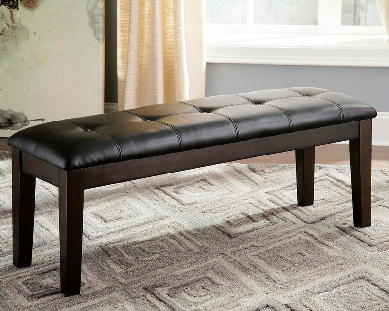 Ashley Furniture Haddigan dining bench with wooden legs and upholstered seat, shown in a modern dining room setting.