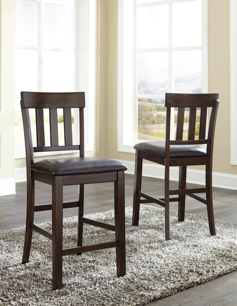 Ashley Furniture Haddigan bar stool set featuring four stylish wooden stools with upholstered seats and metal footrests.