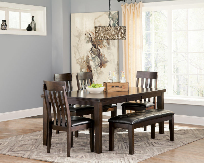Ashley Furniture Haddigan dining extension table with a wooden finish, shown extended with matching chairs.