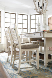 Ashley Furniture Bolanburg counter height dining table with a wood finish, shown with chairs in a modern dining room setting.