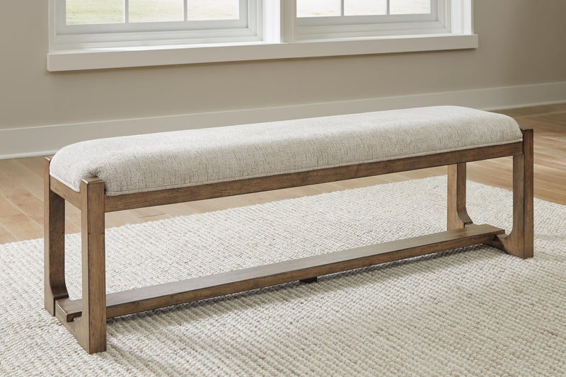 Ashley Furniture Cabalynn 63-inch wooden dining bench with a cushioned seat and sturdy legs, ideal for kitchen or dining room seating.