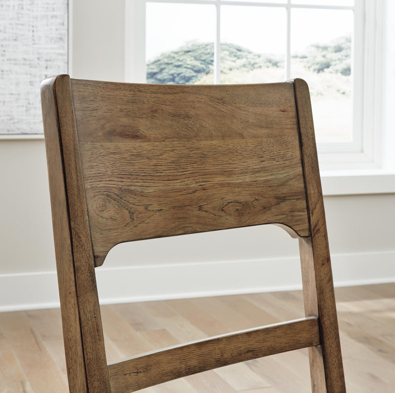 Back view of Ashley Furniture Cabalynn dining room set with wooden table and matching chairs, showcasing the detailed backrests.