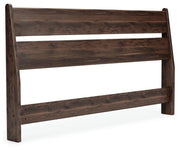 Ashley Furniture Calverson Bed with a sleek wooden frame and angled headboard, shown in a stylish bedroom setting.