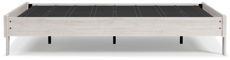 Ashley Furniture Shawburn Queen platform bed with a sleek frame and neutral fabric upholstery, shown from a side view.