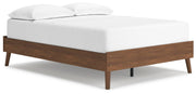 Ashley Furniture Fordmont Bed with a sturdy wooden frame, shown from a side angle in a cozy bedroom setting.