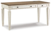 Ashley Furniture Realyn home office set with desk and chair, shown from a side angle in a well-lit room setting.