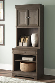 Ashley Furniture Janismore bookcase with multiple shelves and a dark wood finish, ideal for home storage and display.