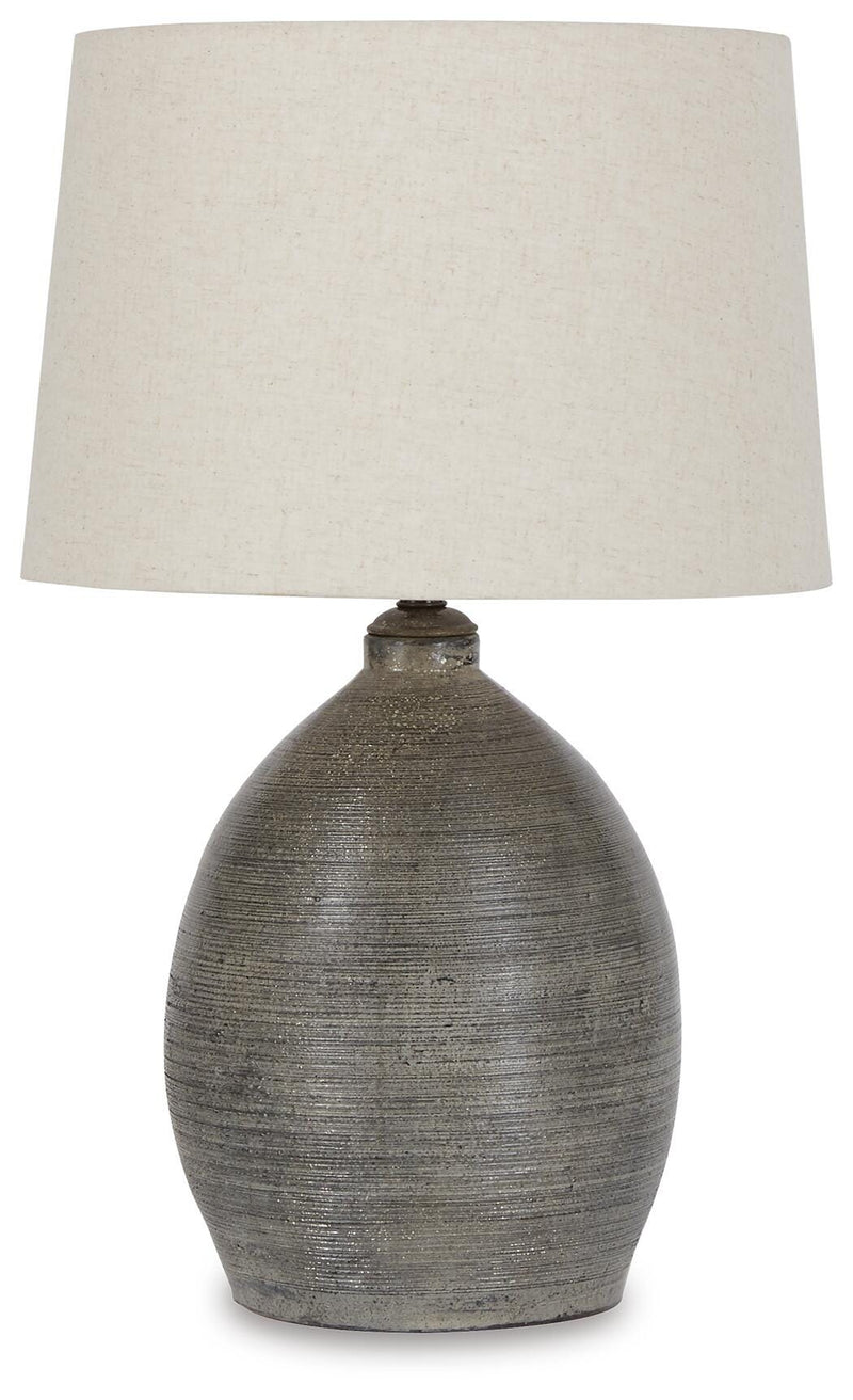 Joyelle table lamp by Ashley Furniture with a sleek design, featuring a white shade and metallic base on a wooden table.