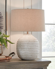 Ashley Furniture Jamon table lamp with a sleek, modern design featuring a white fabric shade and a dark metal base.