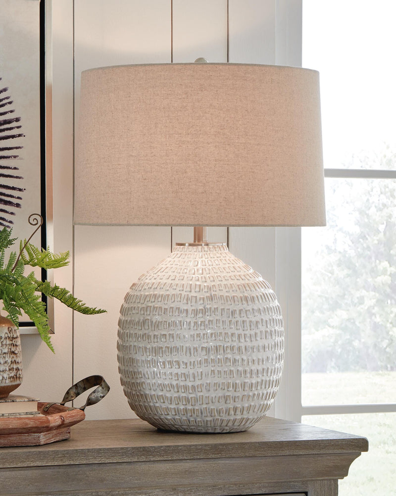 Ashley Furniture Jamon table lamp with a sleek, modern design featuring a white fabric shade and a dark metal base.