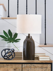 Ashley Furniture Jyler table lamp with a sleek, modern design featuring a white shade and metallic base on a wooden surface.