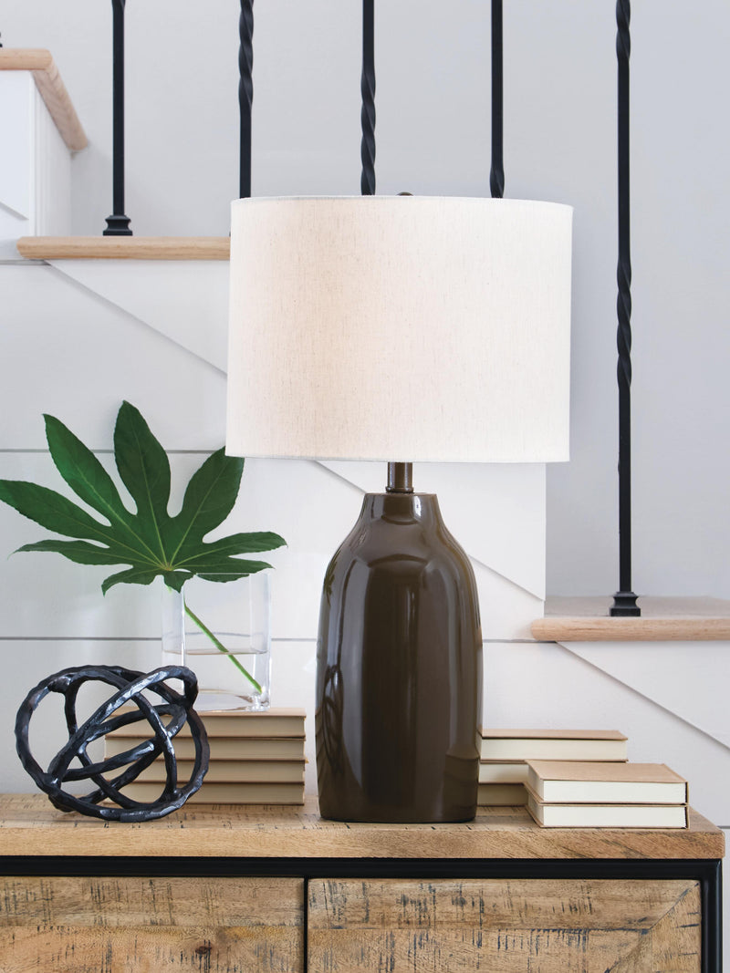 Ashley Furniture Jyler table lamp with a sleek, modern design featuring a white shade and metallic base on a wooden surface.