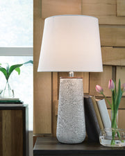 Pair of Ashley Furniture Chaston table lamps with beige fabric shades and ceramic bases, placed on a wooden side table.