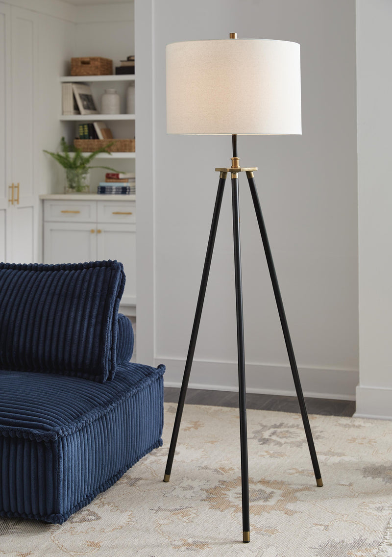 Ashley Furniture Cashner floor lamp with a sleek metal stand and fabric shade standing on a living room floor.