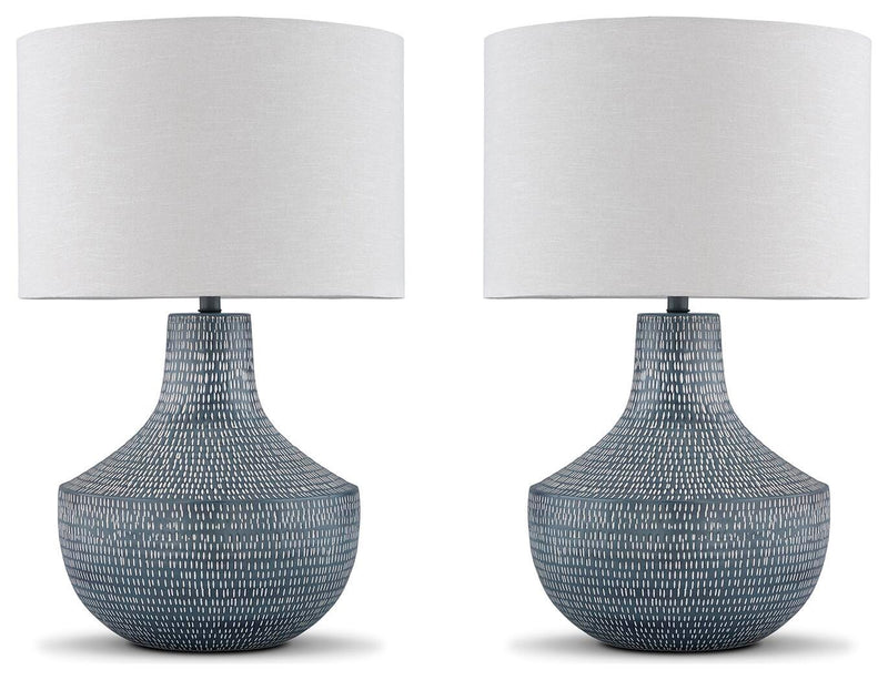 Set of two Ashley Furniture Schylarmont table lamps with beige fabric shades and carved base designs on a wooden surface.