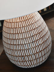 Ashley Furniture Darrich table lamp with a ceramic base and fabric shade, placed on a wooden side table in a modern living room.
