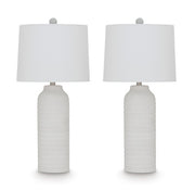 Pair of Vauville table lamps by Ashley Furniture with beige fabric shades and dark wood bases, placed on a wooden surface.