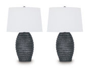 Pair of Ashley Furniture Caronick table lamps with beige fabric shades and dark wood bases on a wooden table.