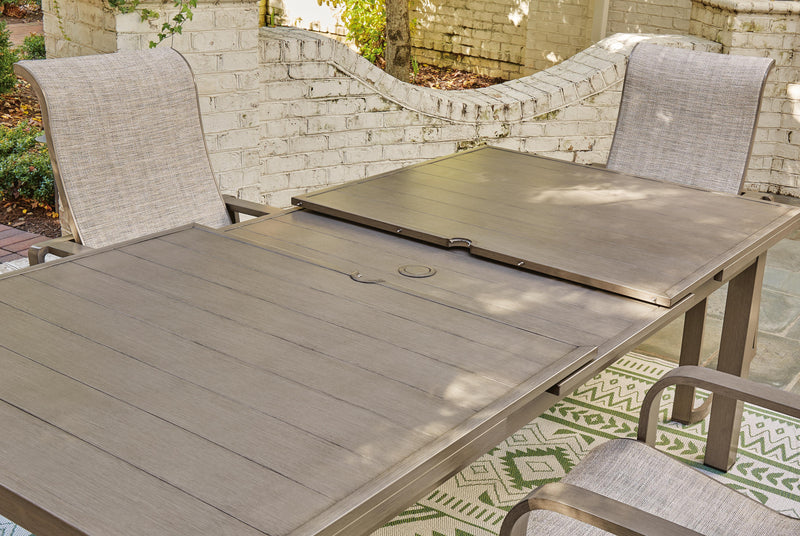 Outdoor Ashley Furniture beach front dining table with wooden top and metal legs, set for outdoor dining by the water.