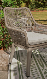 Set of two Ashley Furniture outdoor dining beach front arm chairs with cushions, featuring woven rattan design and sturdy frames.