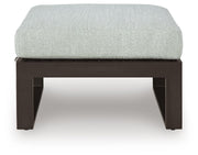 Ashley Furniture Beachloft outdoor ottoman with cushion, showing a stylish outdoor seating piece in a garden setting.