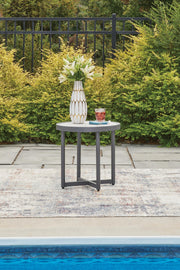 Ashley Furniture Ocean Beach outdoor end table with a woven rattan design and sturdy metal frame for patio or garden use.