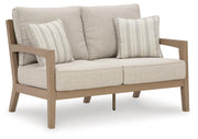Ashley Furniture Hallow Creek outdoor loveseat with cushion, showing a cozy outdoor seating area with woven frame and plush cushion.