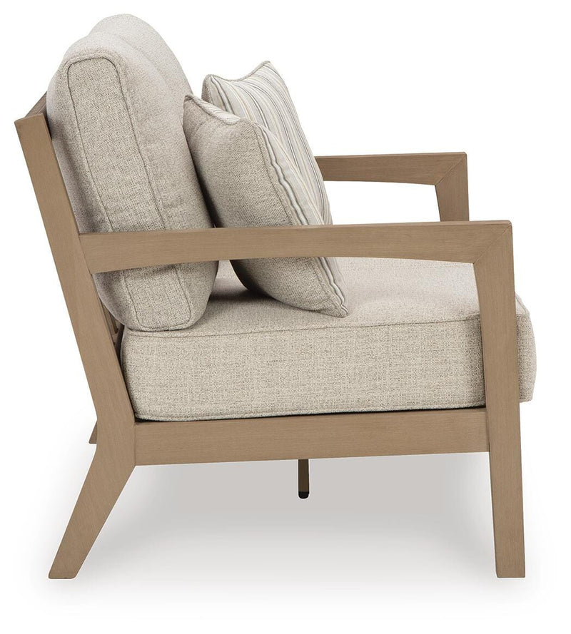 Ashley Furniture Hallow Creek outdoor loveseat with a cushion, featuring a sturdy frame and comfortable seating for outdoor relaxing.