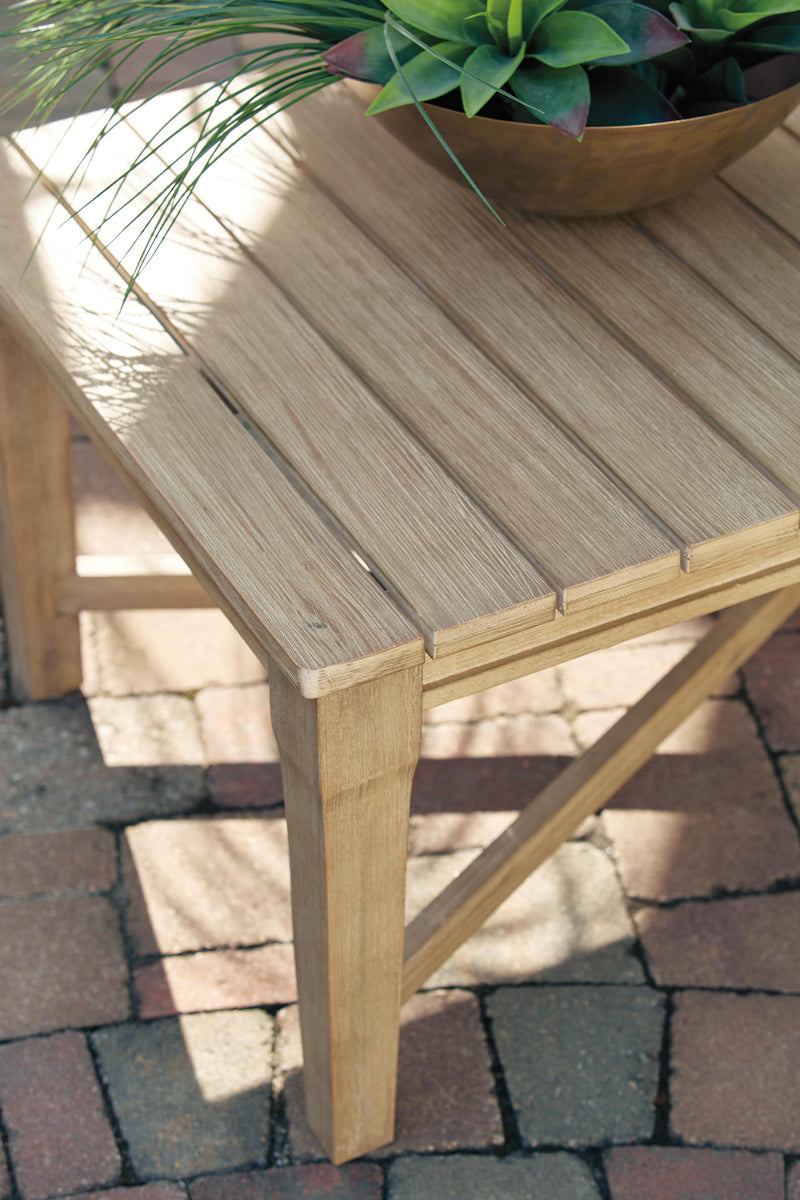 Ashley Furniture Carter Hall outdoor table set with a glass-top table and four matching chairs in a garden setting.
