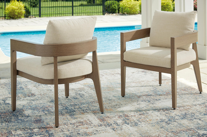 Outdoor dining set by Ashley Furniture featuring a glass-top table and six cushioned chairs in a serene bay setting.