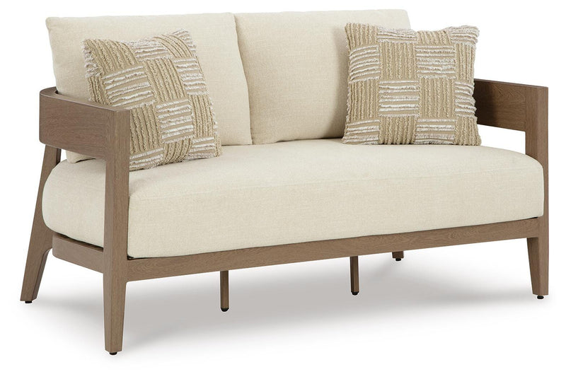 Outdoor loveseat with cushion from Ashley Furniture's Serene Bay collection, shown from an angled view in a cozy outdoor setting.