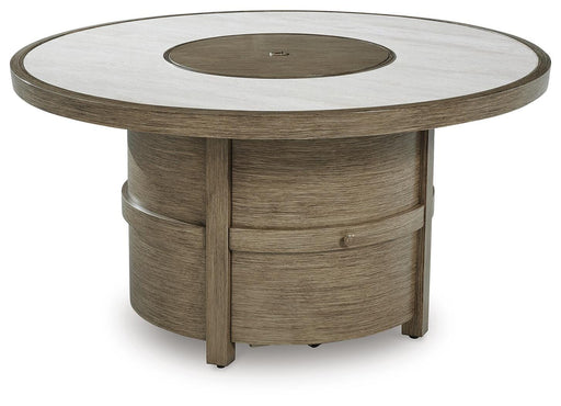 Outdoor Ashley Furniture Rainier Ranch Fire Pit Table with stone finish and built-in fire bowl, viewed from an angled side perspective.