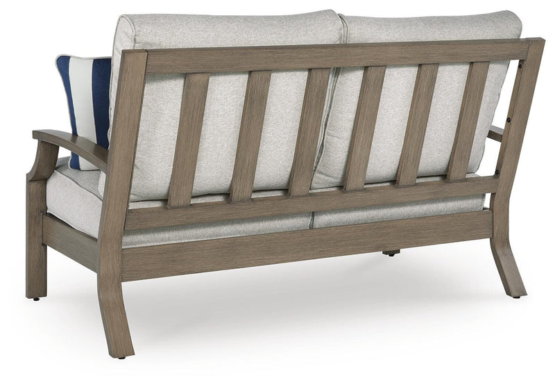 Ashley Furniture Rainier Ranch outdoor loveseat with cushion, showing the back view of the patio furniture piece.
