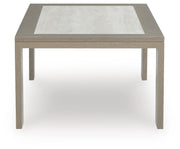 Ashley Furniture Kimpton Isle outdoor cocktail table with a woven rattan design and glass top for patio or garden use.