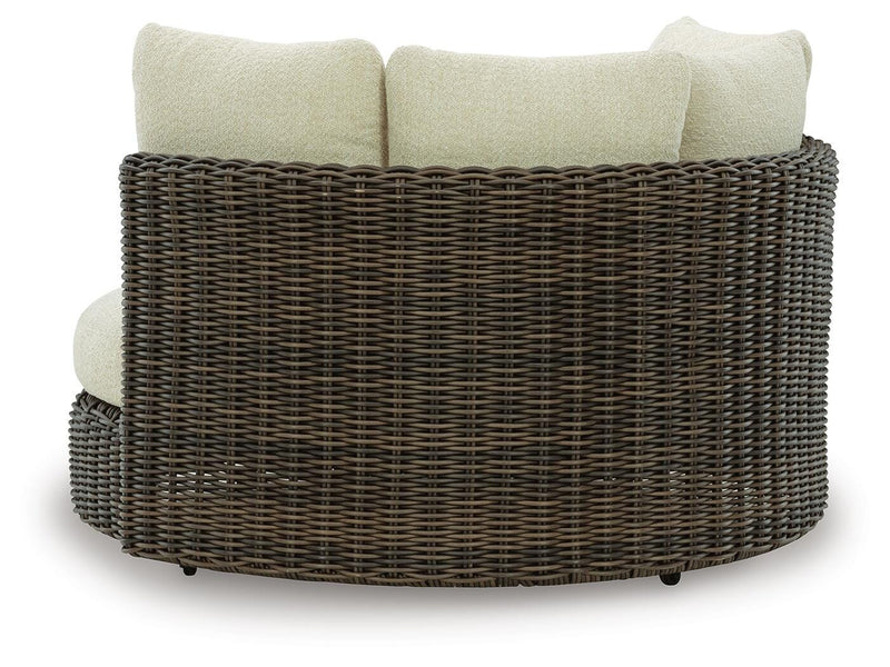 Kimora outdoor swivel lounge chair with cushion by Ashley Furniture, shown from the back with black metal frame and beige cushion.
