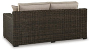 Ashley Furniture Coastline Bay outdoor loveseat with cushions, featuring a stylish patio seating design and comfortable cushion padding.