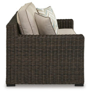 Ashley Furniture Coastline Bay outdoor loveseat with cushion, showing a cozy seating area with plush cushions and weather-resistant frame.