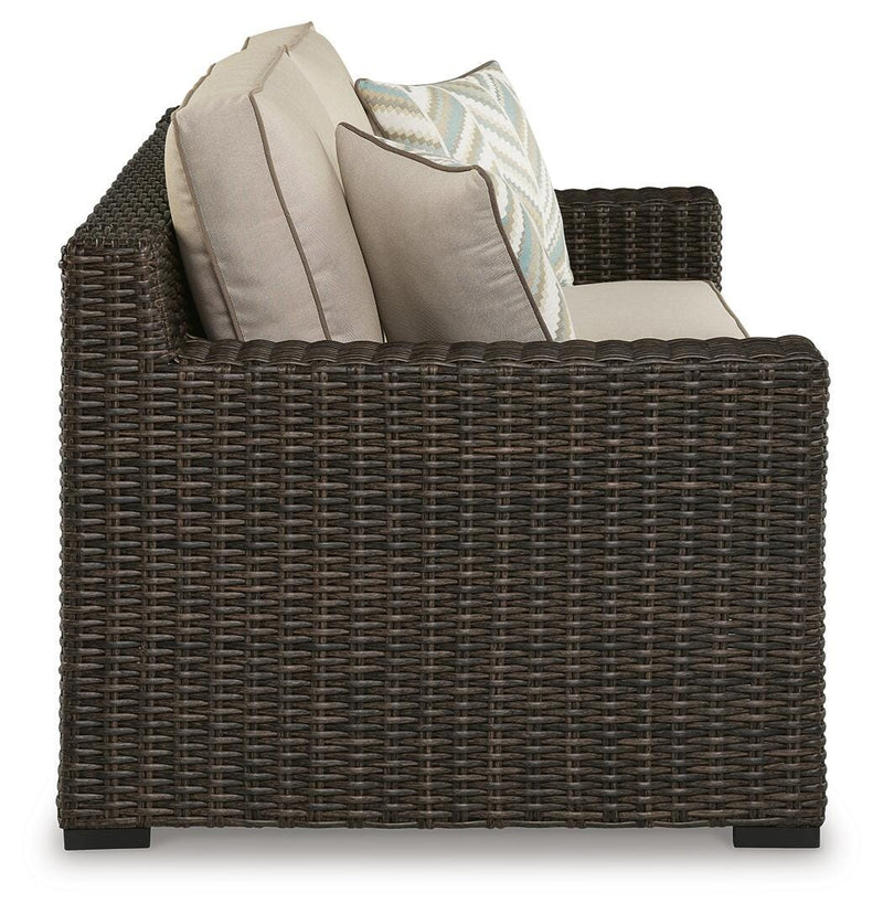 Ashley Furniture Coastline Bay outdoor loveseat with cushion, showing a cozy seating area with plush cushions and weather-resistant frame.