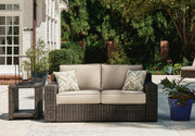 Ashley Furniture Coastline Bay outdoor loveseat with cushion, featuring a sturdy frame and comfortable seating for outdoor relaxation.